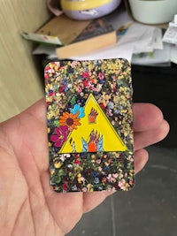 a person is holding a magnet with a flower on it